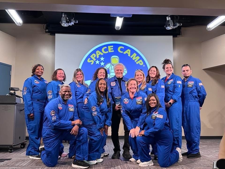 Group of 12 educators pose in front of the Space Camp sign with the Space Camp for Educators instructor