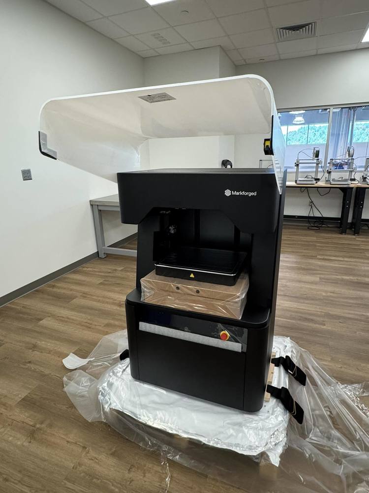 Markforged hybrid FX10 3D printer. The printer is located in the Additive Manufacturing lab. Other 3D printers can be seen in the background.