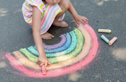 child drawing a rainbow with chalk