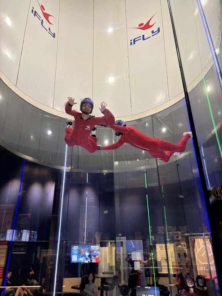 Student does indoor skydiving at iFLY with the help of an instructor.