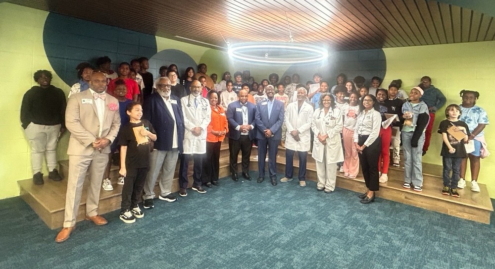 A large group of students, educators, and healthcare professionals gather in the library for a group photo after the RHES medical career fair.