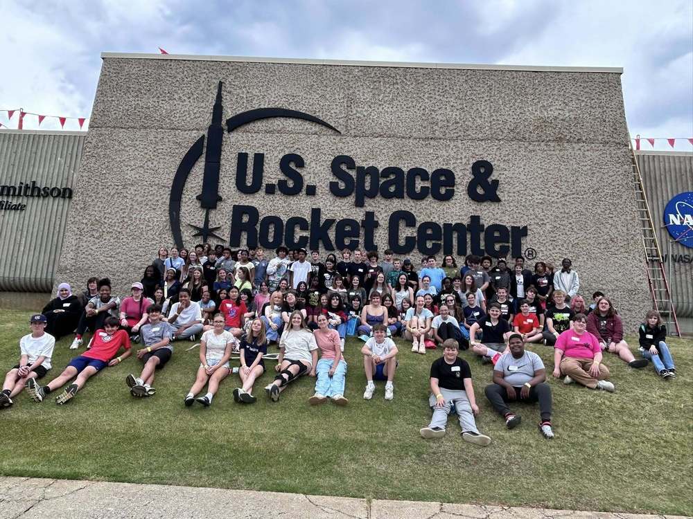 The 8th grade class taking a group picture in front of a sign that says the US Space and Rocket Center