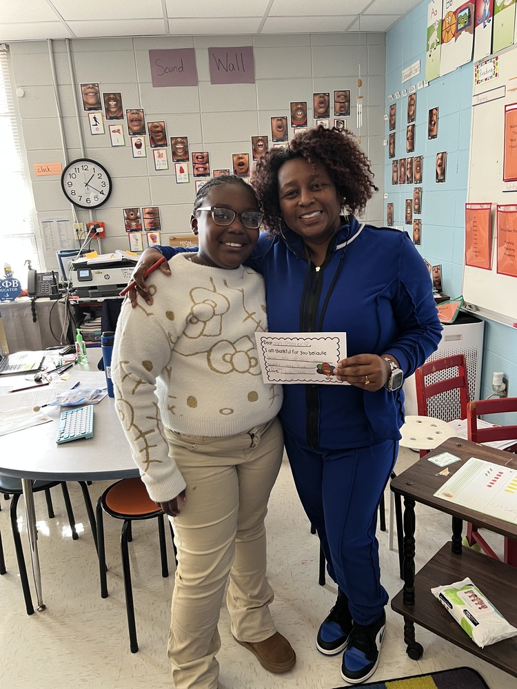 Ms. Danner and a student smiling together while holding a kindness note.