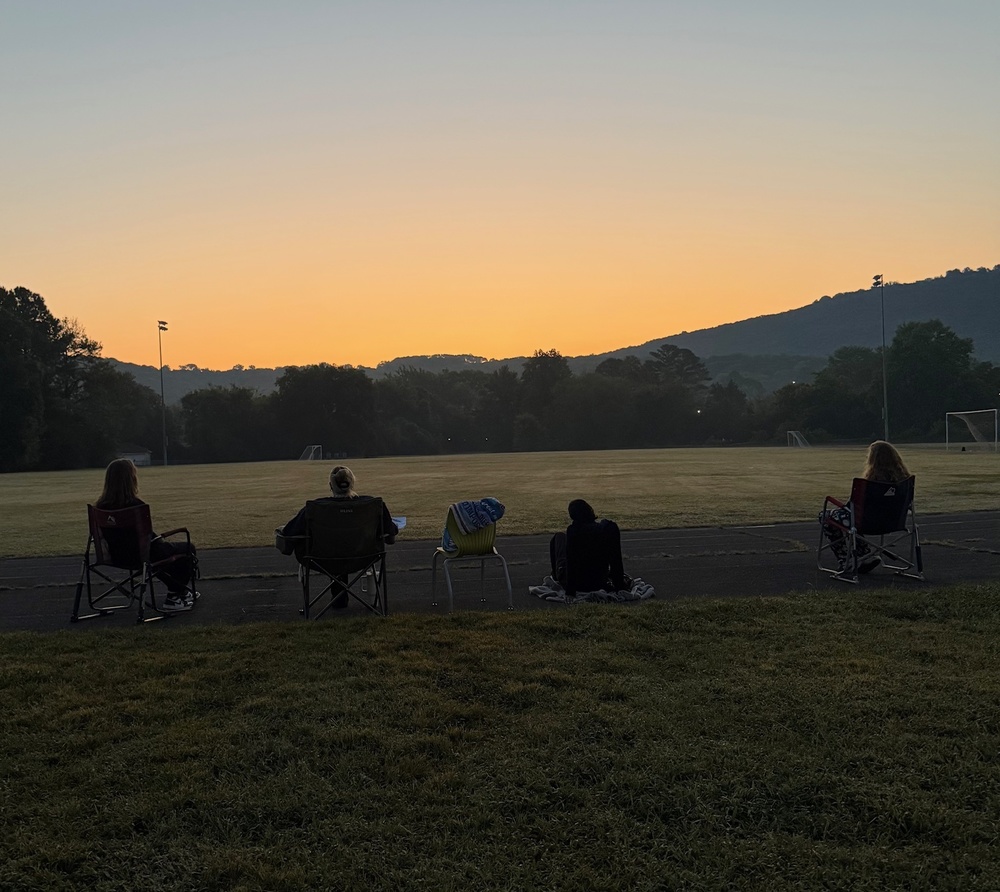 Students sit on the track watching the sunrise. 