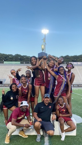 The girls track team with the coaches hoisting the city champions trouphy.