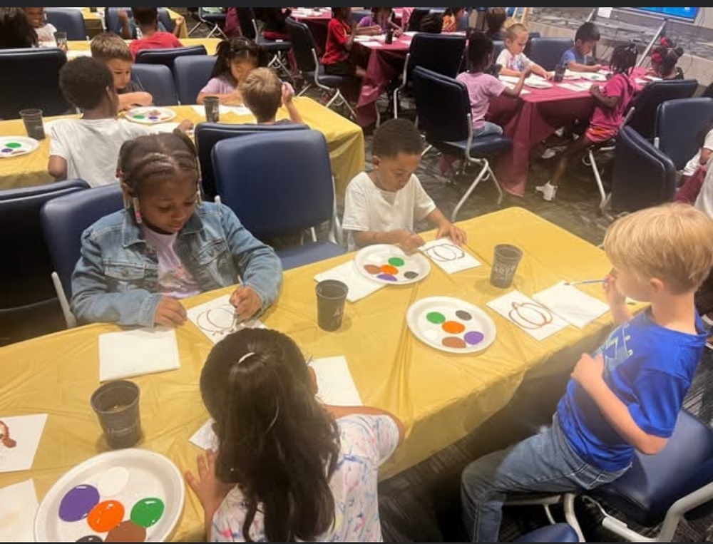 Students sitting at tables painting a pumpkin for their PBIS celebration