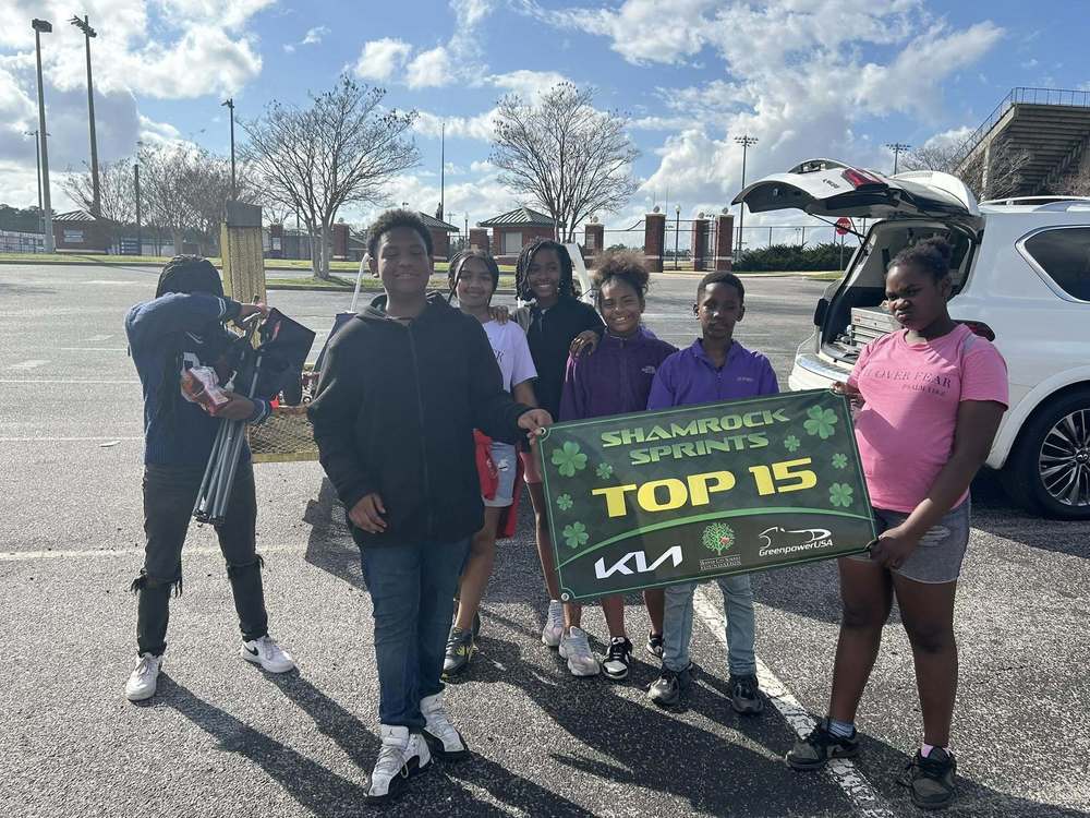 A group of students is standing outside with a banner that reads "Shamrock Sprints Top 15"