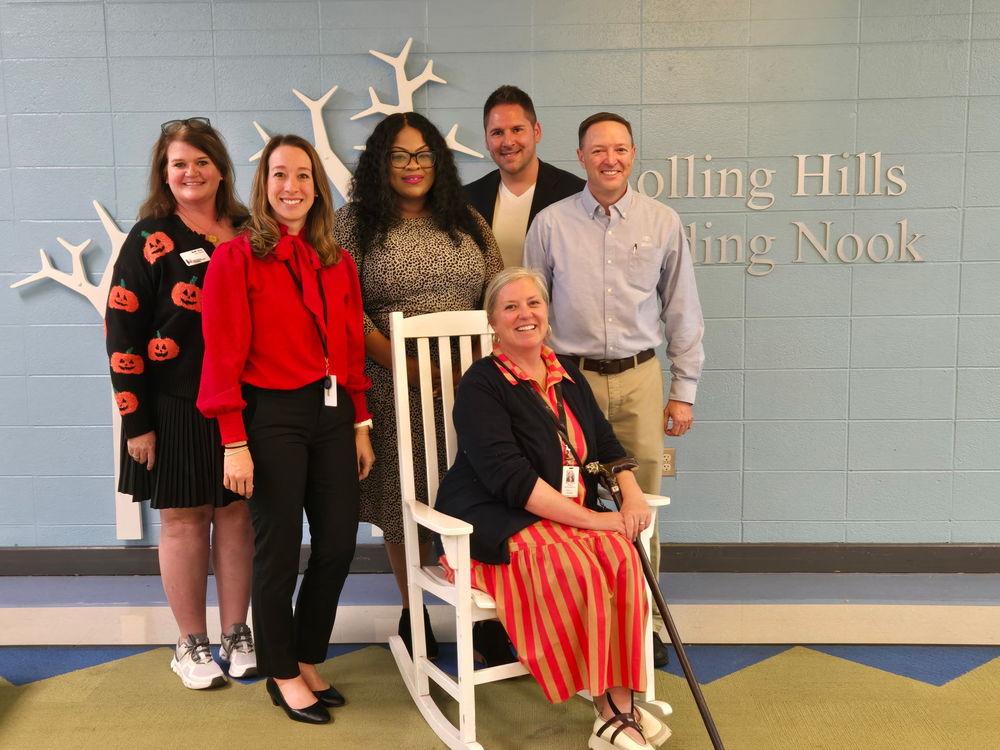 A group of Rolling Hills Elementary staff and community partners smile together in the school’s Reading Nook.