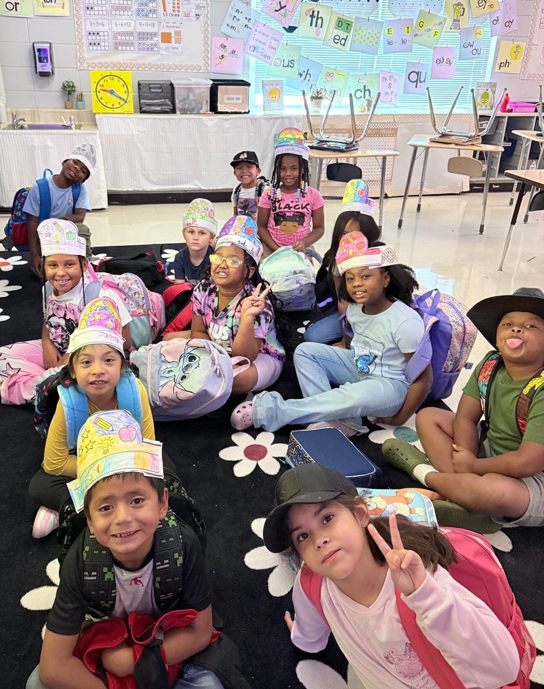Students sitting in a classroom, smiling while wearing their hats