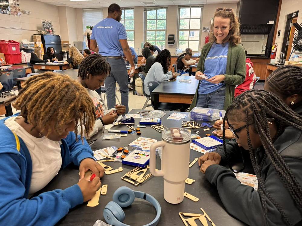 Students at Lee High School assemble solar-powered race cars during a hands-on STEM activity led by Lockheed Martin representatives. The event, held in Earth and Space Science, Forensics, and Biology classes, introduced students to real-world applications of science and technology. A Lockheed Martin engineer (center) provides guidance as students collaborate on their projects.