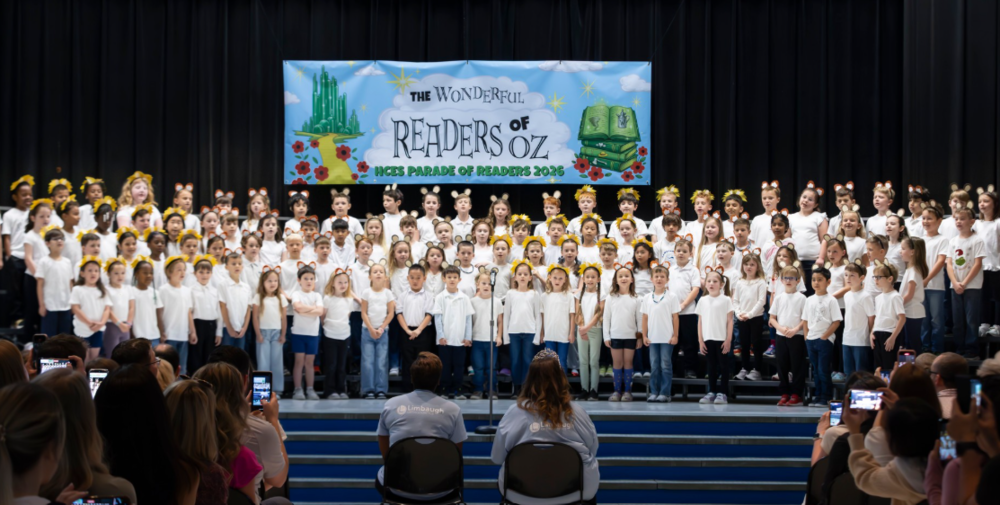 1st grade class standing at the front of the auditorium singing to parents and staff at the Parade of Readers assembly.