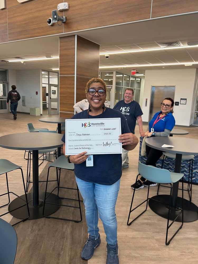 Tonya Robinson standing with her Support Person of the Year check in the Career Tech Center.