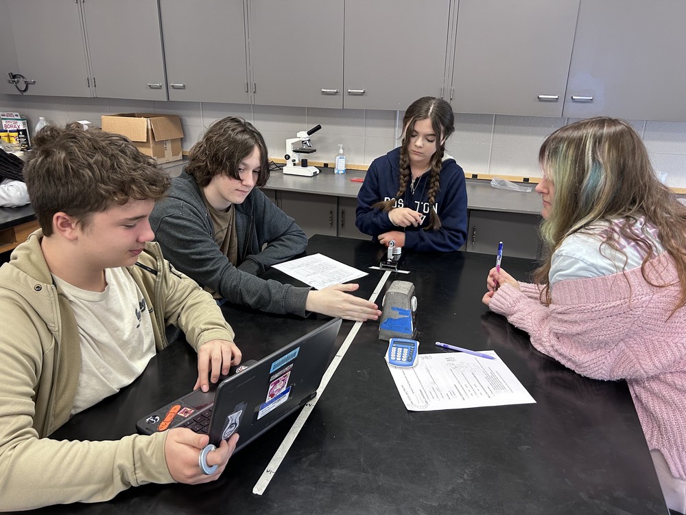 Four students doing an experiment with a fan car to explore Newton's 2nd Law of Motion