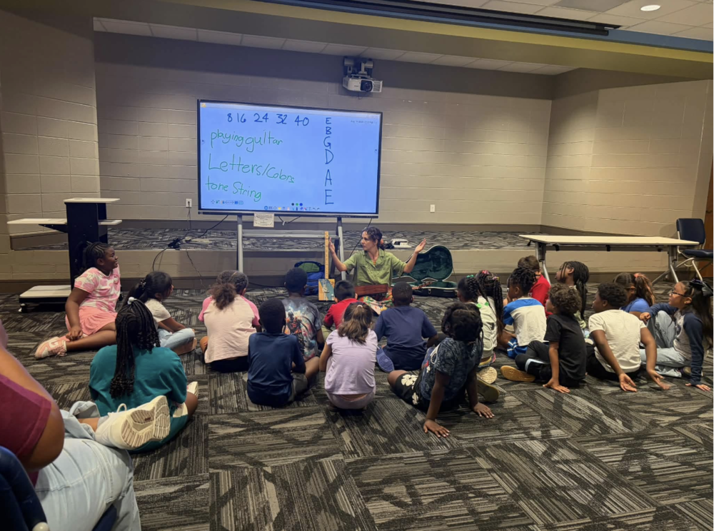 students sitting on the carpet learning math through music from the musician Calliope