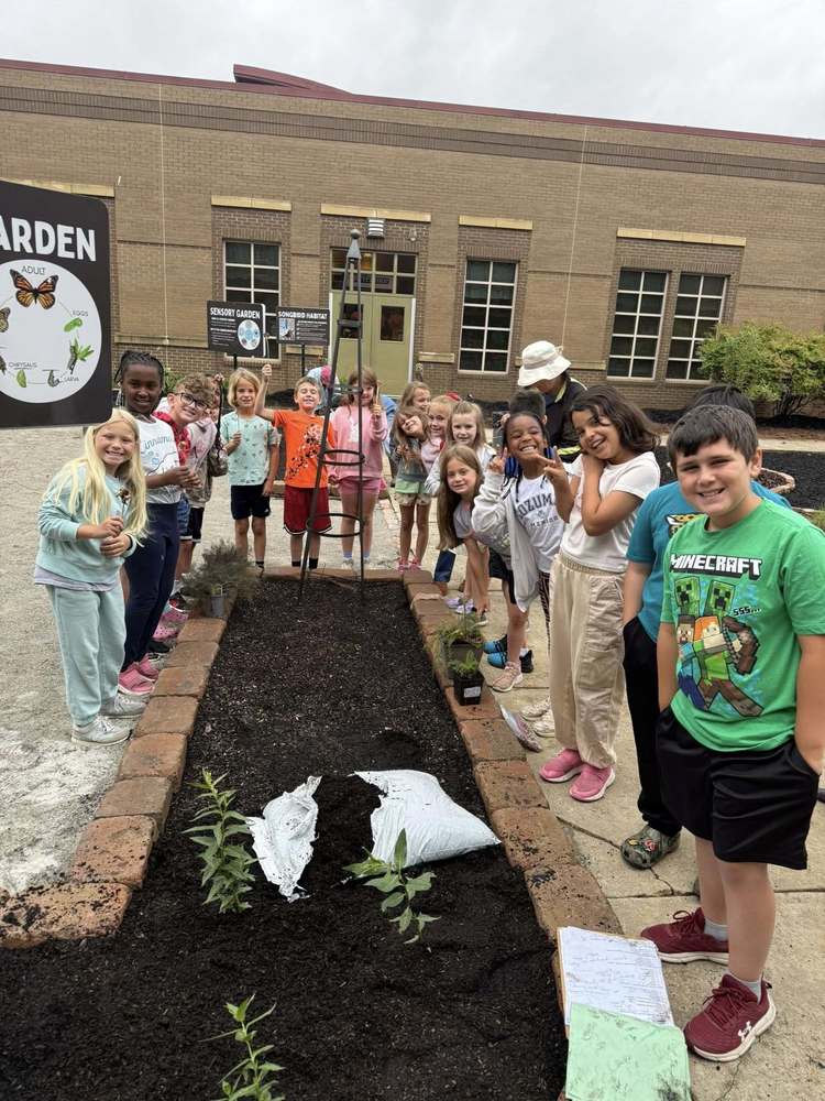 Students and volunteers stand around a garden bed in the Goldsmith outdoor classroom in the courtyard.