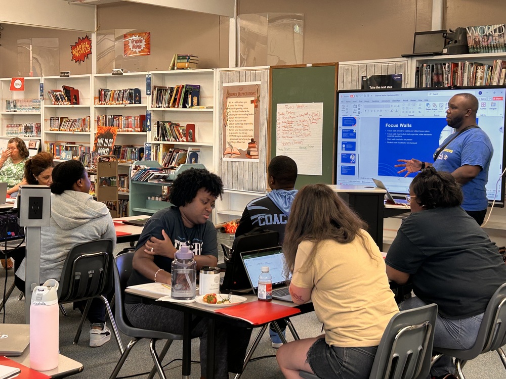 Chapman Middle staff is gathered around tables, engaged in professional development led by assistant principal, John Thornton, in the school library.