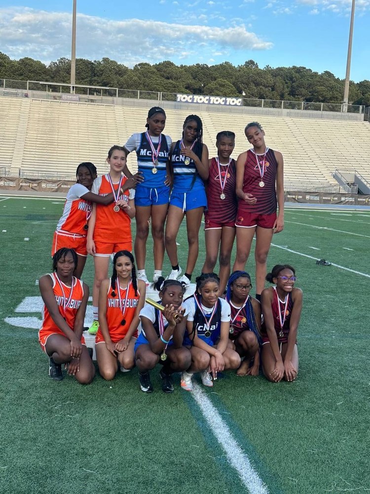 HCS Track Meet with girls on the field in two rows from 3 different HCS schools and medals