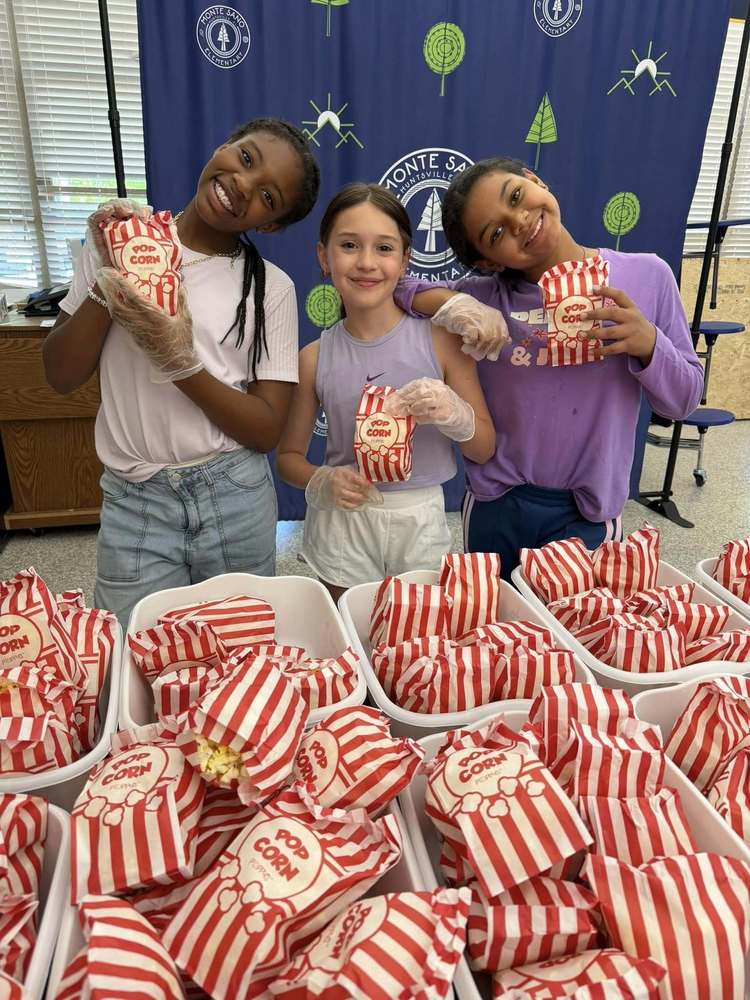 Three students standing in front of popcorn for popcorn movie party