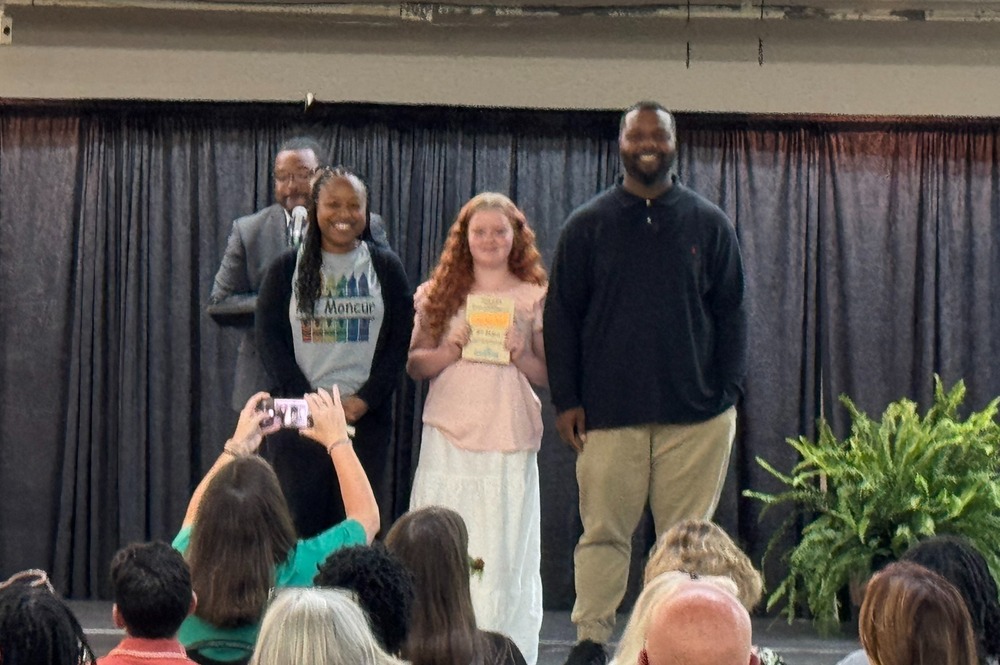 Ms. Moncur, Ayla Stringer, and Mr. Manuel on stage accepting the Green Ambassador School award for Chapman Middle School. 