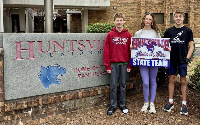 huntsville junior high sign with three student swimmers