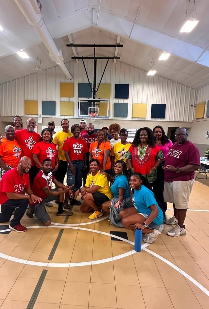 Several people posing in the gym dressed in red, blue, and yellow shirts female and males