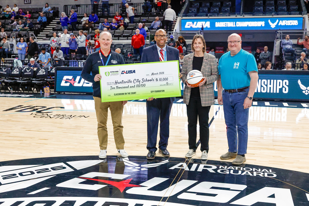 Dr. Sutton accepts the game ball and a grant check for $10,000 from the Conference USA Basketball Tournament