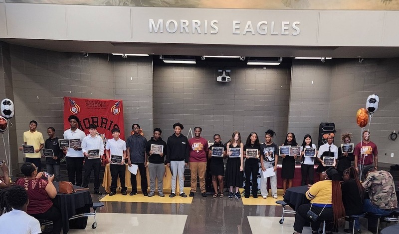 Student-athletes posing with certificates and awards