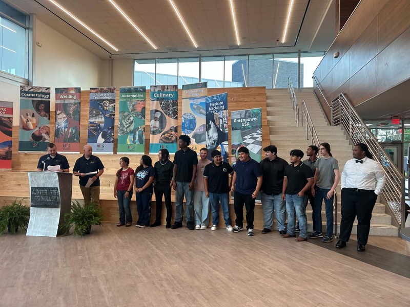 Multiple welding students line up to received their certificates from the two welding instructors.