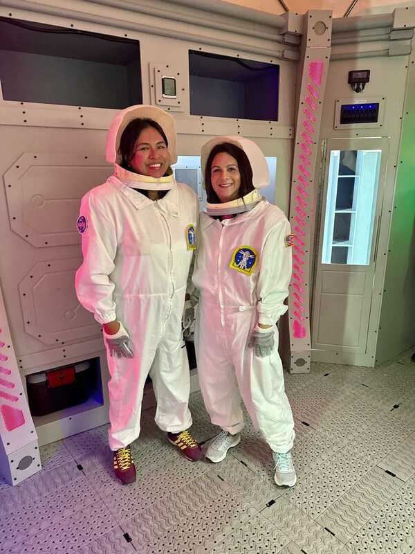 Two educators pose for a photo while wearing space suits