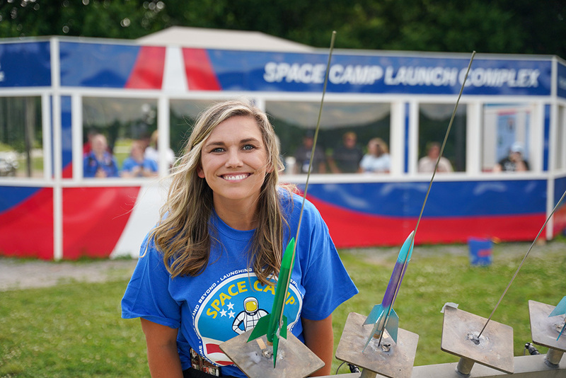 Teacher smiling in front of her model rocket at space camp launch complex