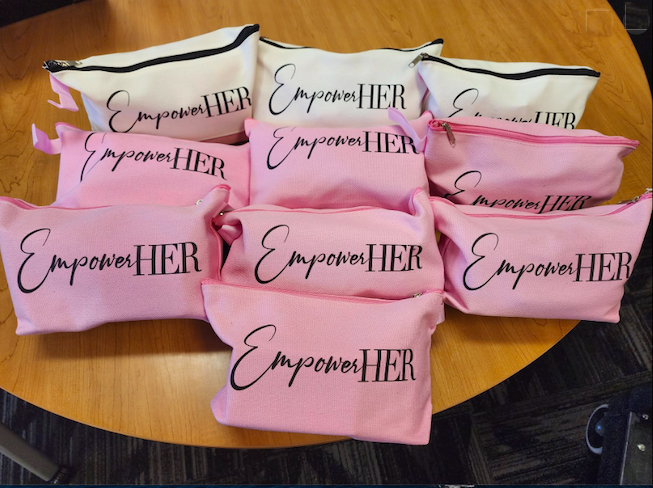 A group of small zippered bags with the words "Empower Her" printed on them.