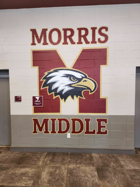 A mural on a beige wall featuring the words "Morris" at the top and "Middle" at the bottom. In the center is a large letter M with a the face of an eagle centered on it. The colors are crimson, white, black and gold.