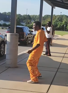 A dad dressed in orange joins Mr. Palmer and students in our Friday Morning Carline Dance Party
