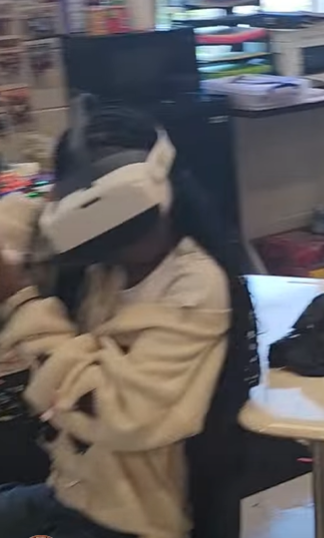 A student tilts her head while maneavering items in virtual reality. She's wearing a white headset.