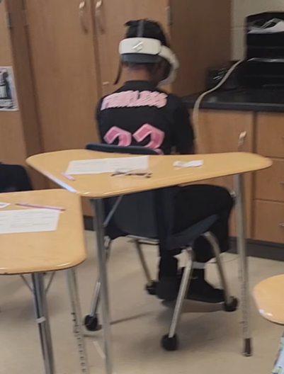 A student has her back turned so that she doesn't accidentally bump her neighbors while using the VR headset