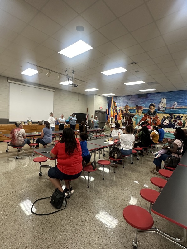 A view of parents in the cafeteria listening to the presentation.