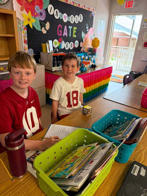 two students sitting at table with books in front of them