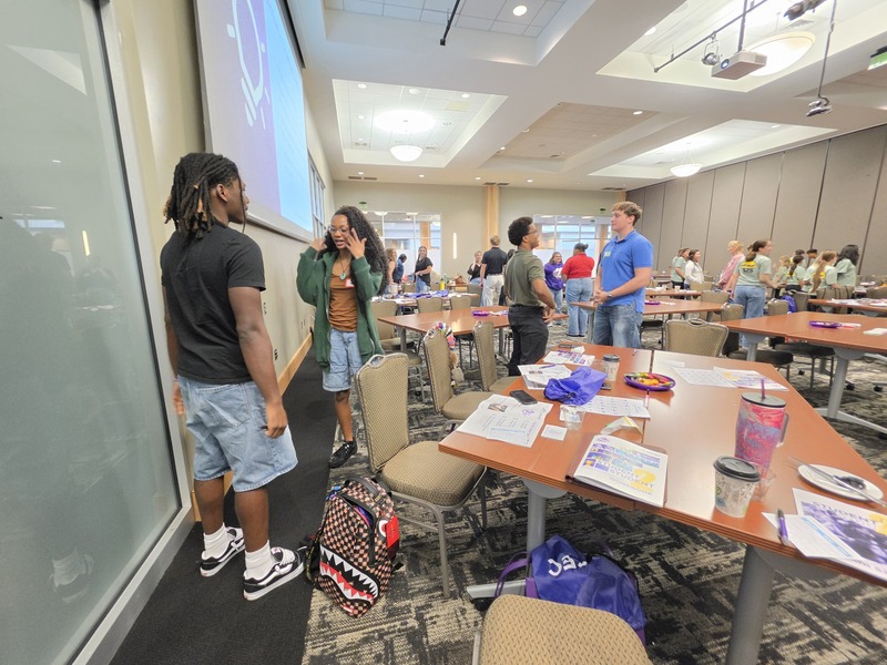 Student 2 Student members from Columbia in groups in front of table of activities doing an activity at the summit