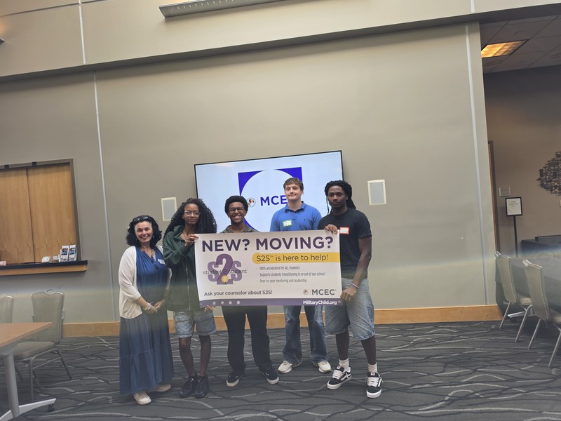 S2S Sponsor, Ms. K and four students hold Purple STAR banner that reads, New? Moving? while posing for picture