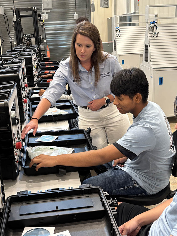 A LIGHT instructor showing a student how to operate a piece of equipment