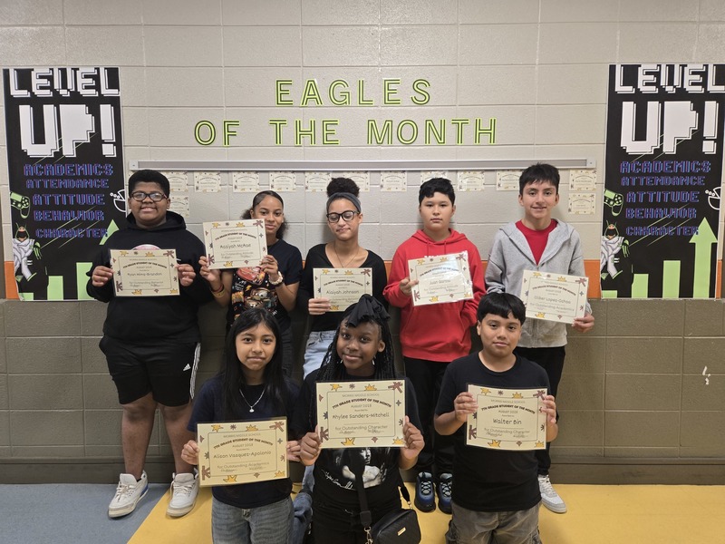 8 Winner's for August stand in front of a sign that says "Eagles of the Month"