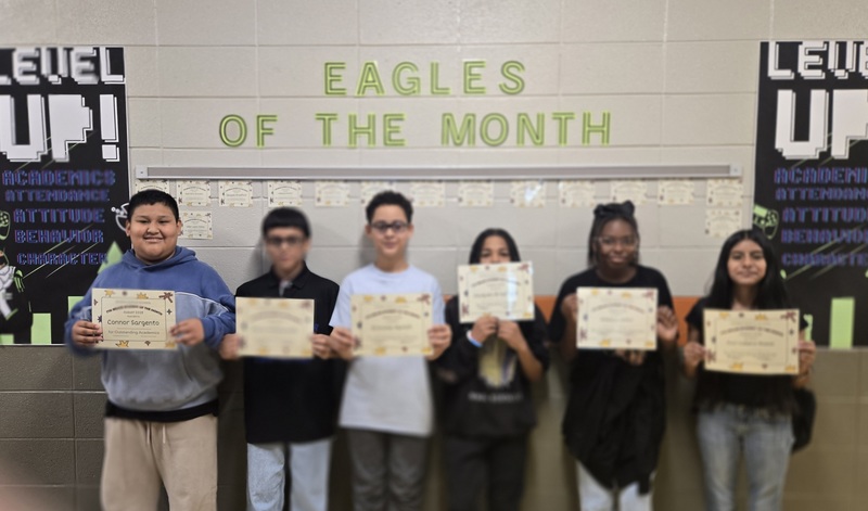 6 students stand in front of a sign reading Eagles of the Month