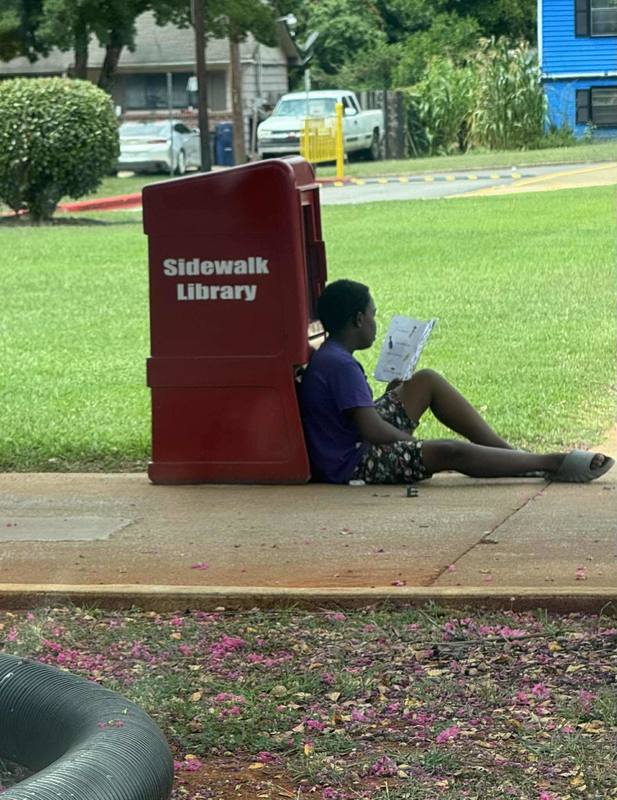 Student reading a book next to the Ridgecrest Sidewalk Library