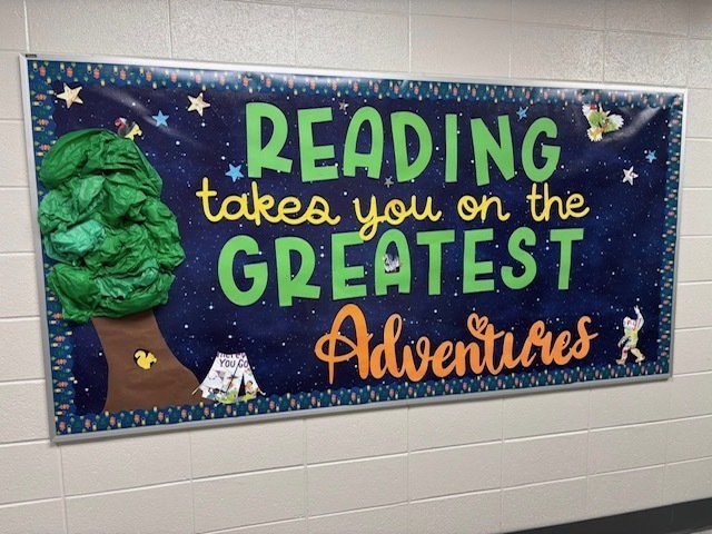 Our library bulletin board says Reading Takes You on the Greatest Adventures with a yeti and a big tree