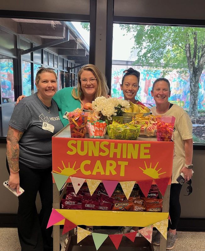 Weatherly PTA  standing behind a decorated snack cart labeled "SUNSHINE CART" with snacks and flowers.