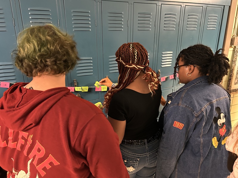 Several students are discussing the placement of rational numbers on the number line in the hallway.