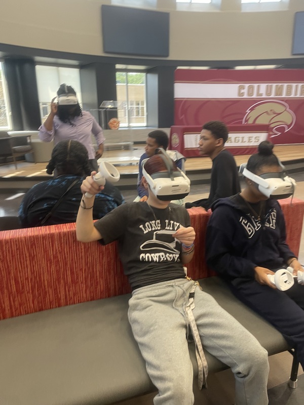 Teacher in front of students sitting with VR headsets on during a lesson in the library
