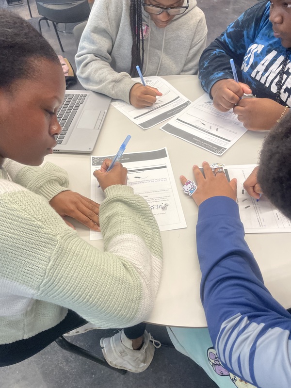 Four students in the library seated  working on with lesson about DNA structure 