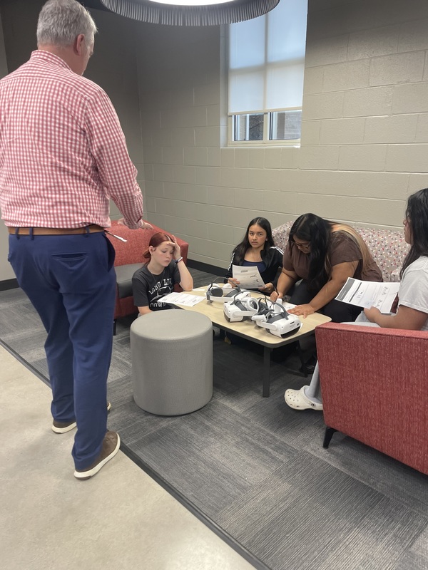 Dr. Buckner in the library discussing with 4 students at table, seated in library working on DNA lesson