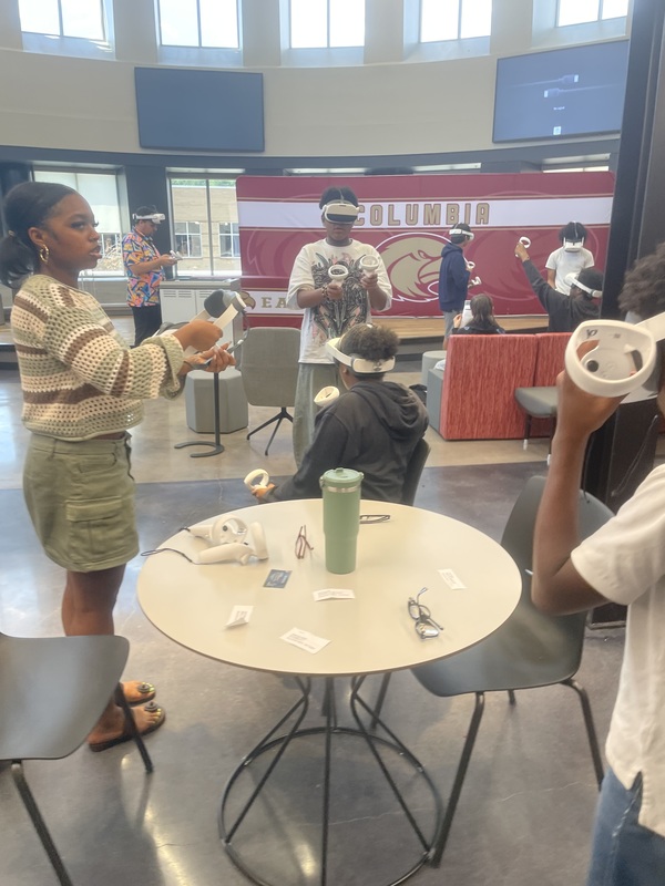 Students standing around in library using VR headsets for lesson on DNA structure